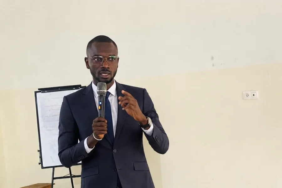 Formateur présentant une session, micro à la main, devant un tableau de papier